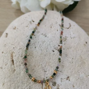Collier de perles d'agate indienne de 3mm, orné d'un petit cactus doré. Il est posé sur une pierre blanche.
