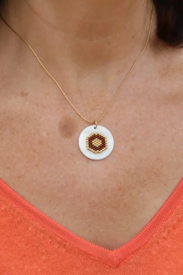 collier tissé bordeaux et blanc sur palet de nacre, porté sur peau avec un t-shirt en V orange