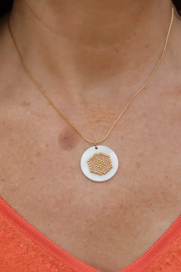 collier tissé rose pale et doré, porté sur peau avec T-shirt en V orange.
