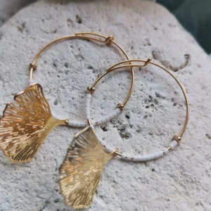 Créoles plaquées or 24k de 30mm, ornées de perles Miyuki blanches et d'un pendentif Ginko doré posées sur une pierre blanche