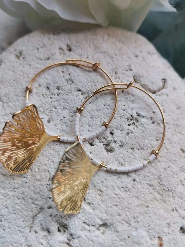 Créoles plaquées or 24k de 30mm, ornées de perles Miyuki blanches et d'un pendentif Ginko doré posées sur une pierre blanche