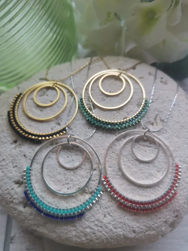 Ensemble de Colliers 3 anneaux dont le grand est tissé de perles Miyuki. Dorés ou argentés, ils sont posés sur une pierre blanche.