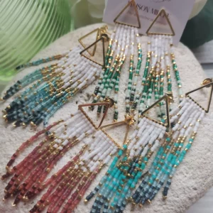 Ensemble de boucles triangles dorées avec fils de perles Miyuki en dégradé de rose, de bleu et de vert. Toutes posées sur une pierre blanche.