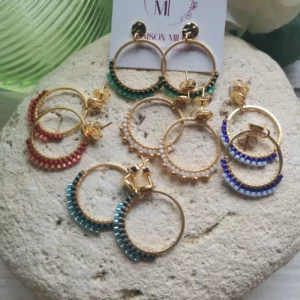 Ensemble de Clous d'oreilles froissés en acier inoxydable avec anneau tissé de perles Miyuki de différentes couleurs. Le tout posé sur une pierre blanche.