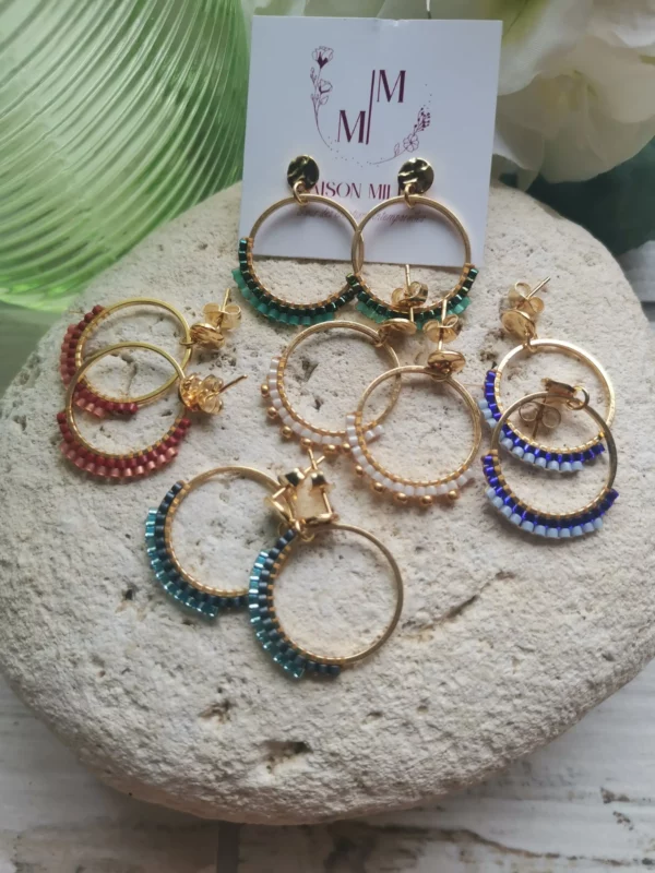Ensemble de Clous d'oreilles froissés en acier inoxydable avec anneau tissé de perles Miyuki de différentes couleurs. Le tout posé sur une pierre blanche.